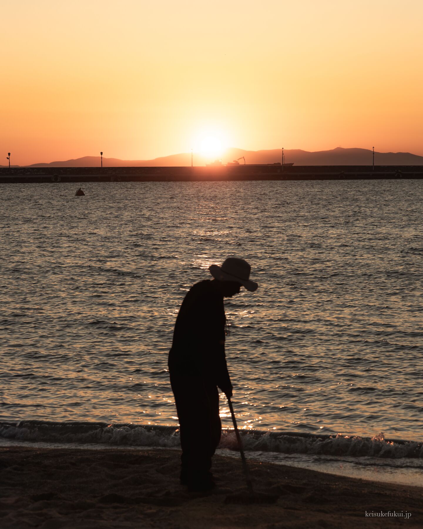 夕日の海辺に立つ人